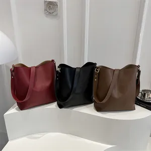 Sacs seaux minimalistes en cuir en bordeaux, noir et fauve sur un support géométrique