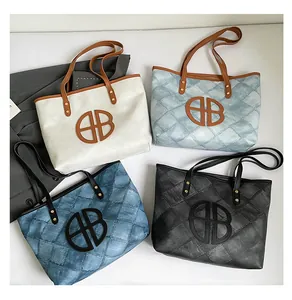 Flat lay of four textured tote bags in white, blue, and black with large AB logo