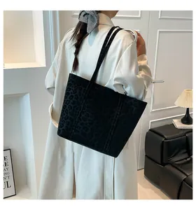 Detail of black leopard print tote bag texture paired with a beige trench coat