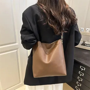 Sac seau chic en cuir marron pour femme porté avec un blazer noir pour un look de bureau