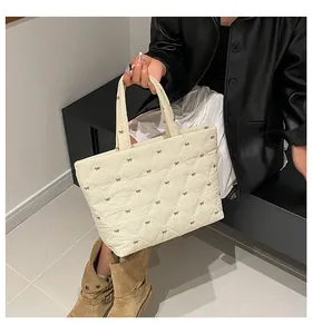 Detail der cremefarbenen Stepptasche mit schwarzen Schleifenstickereien und Rautenmuster