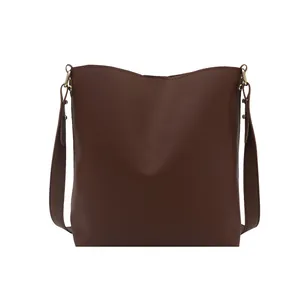 Sac seau minimaliste en cuir marron foncé avec large bandoulière et détails dorés