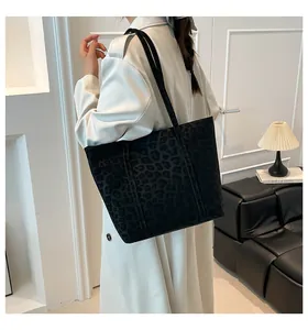 Detail showing high-capacity black leopard print tote bag with soft velvet texture