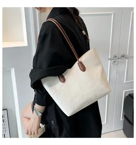 Detail view of large white tote bag with lychee texture and brown shoulder straps