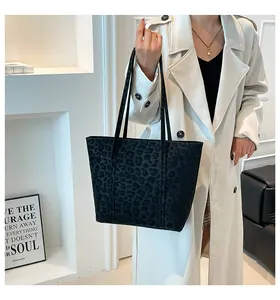 Detail of black leopard print tote bag in suede texture worn with a white coat