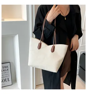 Detail of off-white lychee leather tote bag with V-cut edge and brown shoulder strap