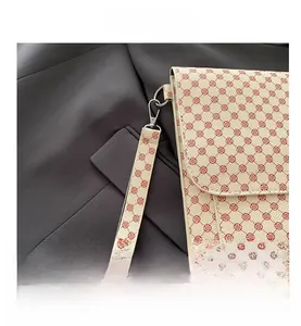 Détail d'un sac enveloppe beige avec motif floral rouge et boucle en métal argenté