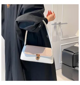 Detail einer zweifarbigen Baguette-Tasche mit beige Kroko-Klappe und goldener Schnalle