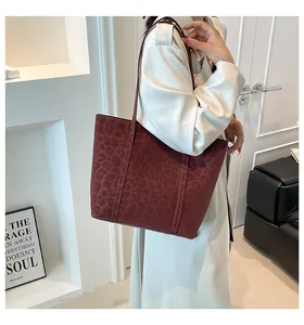 Detail of burgundy leopard print tote bag with matte leather texture and slim straps