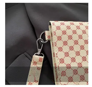 Détail du crochet métallique argenté sur un sac en cuir crème avec motif floral