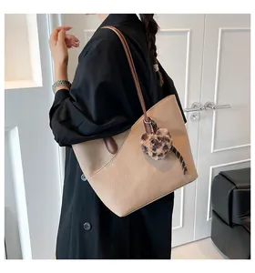 Detail of beige tote bag with litchi texture and brown strap worn on shoulder