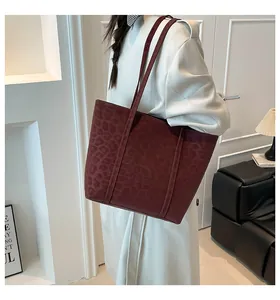 Detail of burgundy leopard print tote bag with long straps worn on shoulder by model