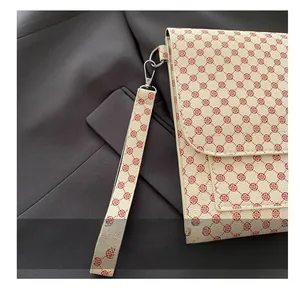Détail d'une pochette enveloppe à motif trèfle rouge avec une dragonne amovible élégante