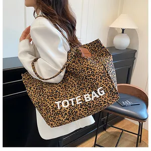 Close-up of leopard print canvas tote bag with white TOTE BAG text and leather detail