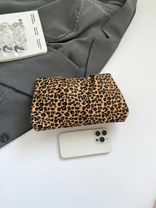Comparaison de taille de la pochette léopard en toile avec un smartphone sur fond sobre