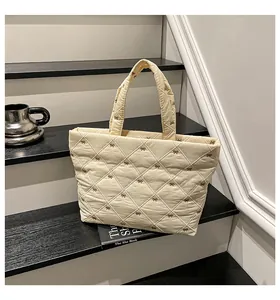 Detail einer cremefarbenen Stepptasche mit feiner brauner Bogenstickerei und weichem Stoff