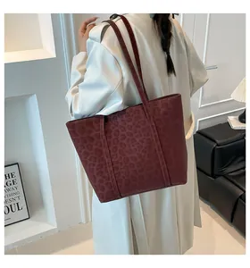 Detail of vintage leopard print tote bag in dark burgundy worn with a beige trench coat
