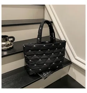 Detail einer schwarzen Stepptasche mit weißem Schleifenstickerei auf minimalistischem Hintergrund
