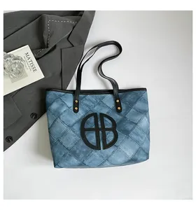 Detail of blue denim tote bag with quilted pattern and bold black BB logo design