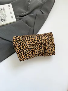 Détail d'une trousse de maquillage à imprimé léopard sur un fond mode avec blazer gris