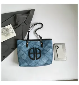 Blue denim texture tote bag with black circular cutout logo on a clean white background