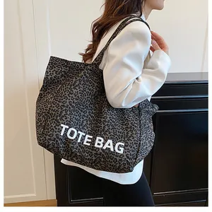 Large leopard print tote bag being worn by a model in a modern indoor setting