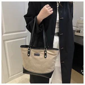 Detail of contrast stitching and FASHION label on quilted canvas tote bag with leather trim
