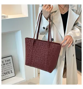 Detail of burgundy leopard embossed tote bag with slim shoulder straps in suede texture