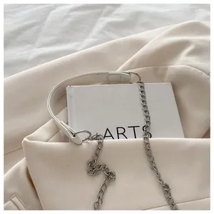 Detail of minimalist beige PU leather crossbody bag with silver chain and wide strap