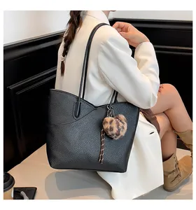 Detail of black pebbled leather tote bag with V-shaped stitching and leopard pompom