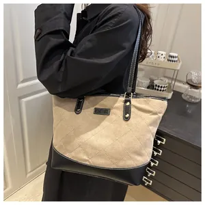 Detail of a khaki canvas tote bag with black leather patchwork and diamond quilting