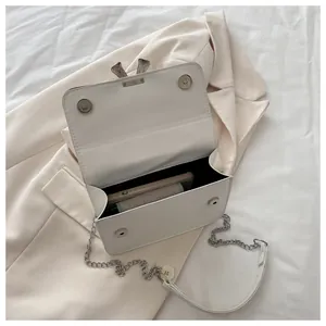 Close-up of white crossbody bag showing interior capacity and silver leaf lock