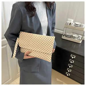 Détail d'un sac à main rétro crème à pois marron tenu par un mannequin en costume gris