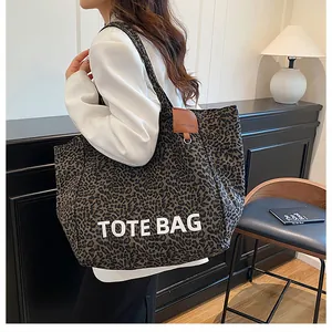 Detail showing the leopard print canvas texture and the bold white TOTE BAG text print