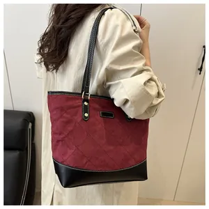 Detail of burgundy quilted tote bag on model shoulder with black leather strap
