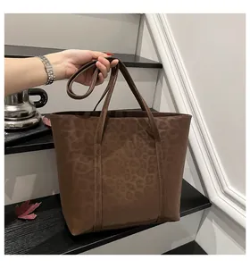 Detail view of large leopard print tote bag with matte texture on indoor stairs