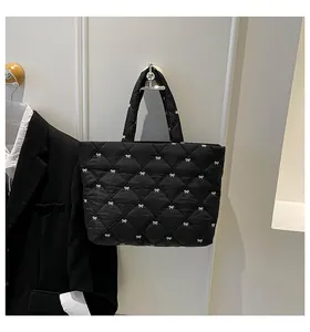 Detail der schwarzen Stepptasche mit weißen Schleifenstickereien an der Wand