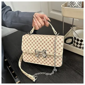 Close-up of a cream crossbody bag with red floral patterns and silver bow buckle detail