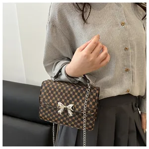 Detail of a brown geometric pattern crossbody bag featuring a silver metal bow buckle