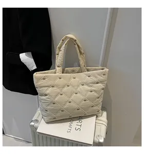 Detail einer gesteppten Tragetasche mit Schleifenstickerei auf einem Koffer