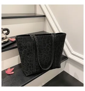 Detail of a large black tote bag with leopard print texture on black staircase