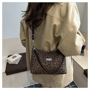 Detail der Leopard-Schultertasche mit schwarzem Logo-Patch und verstellbarem Riemen