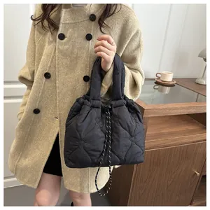 Detail of black heart-quilted puffer tote bag featuring adjustable drawstring closure