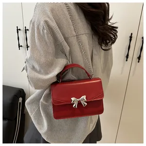 Red leather crossbody bag with silver bow accent shown in a lifestyle model shot