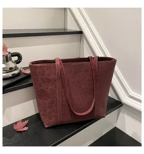 Detail of burgundy leopard print tote bag on a minimalist staircase with autumn leaves