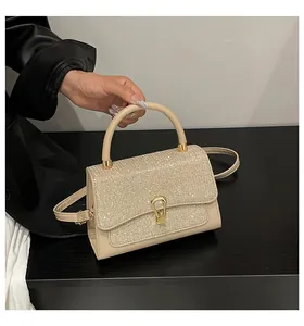 Close-up of beige sequined handbag featuring golden horseshoe lock and leather handle