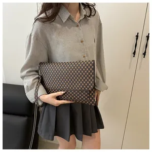 Gros plan sur la pochette vintage à motif géométrique marron et dragonne en cuir
