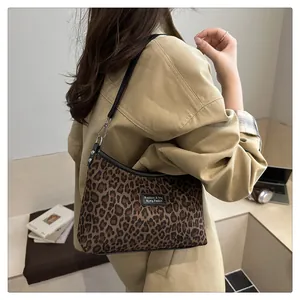 Detail der Schultertasche mit Leopardenmuster und schwarzem Riemen, getragen von Model