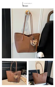 Detailed view of large brown tote bag with pebble texture and leopard heart charm
