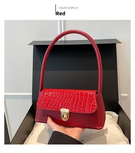 Detail of red baguette bag featuring croc-embossed leather flap and golden metal clasp